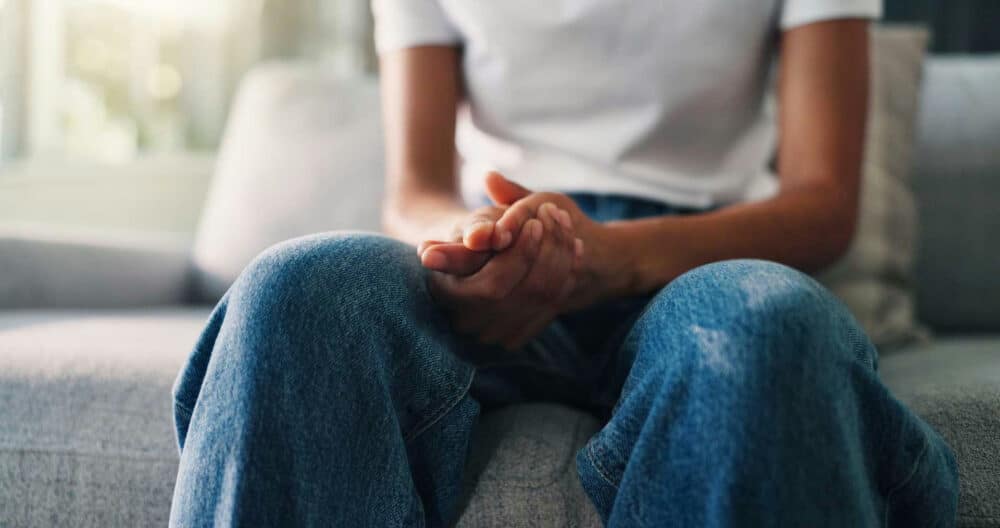 Person sitting with hands clasped, reflecting on personal relapse prevention strategies to stay strong in addiction recovery.
