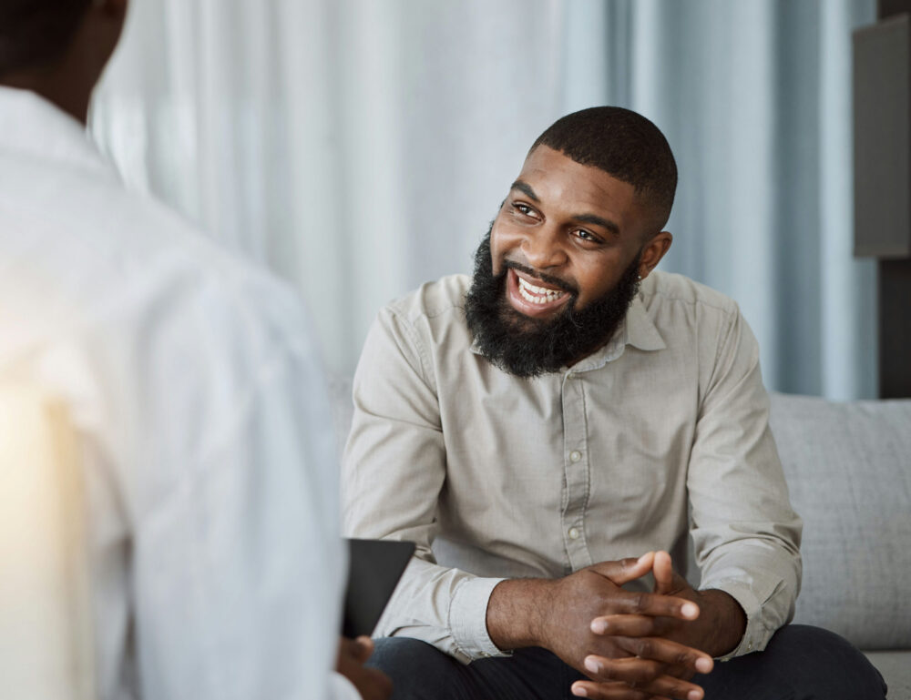 A smiling man engaging with a recovery coach in a supportive session