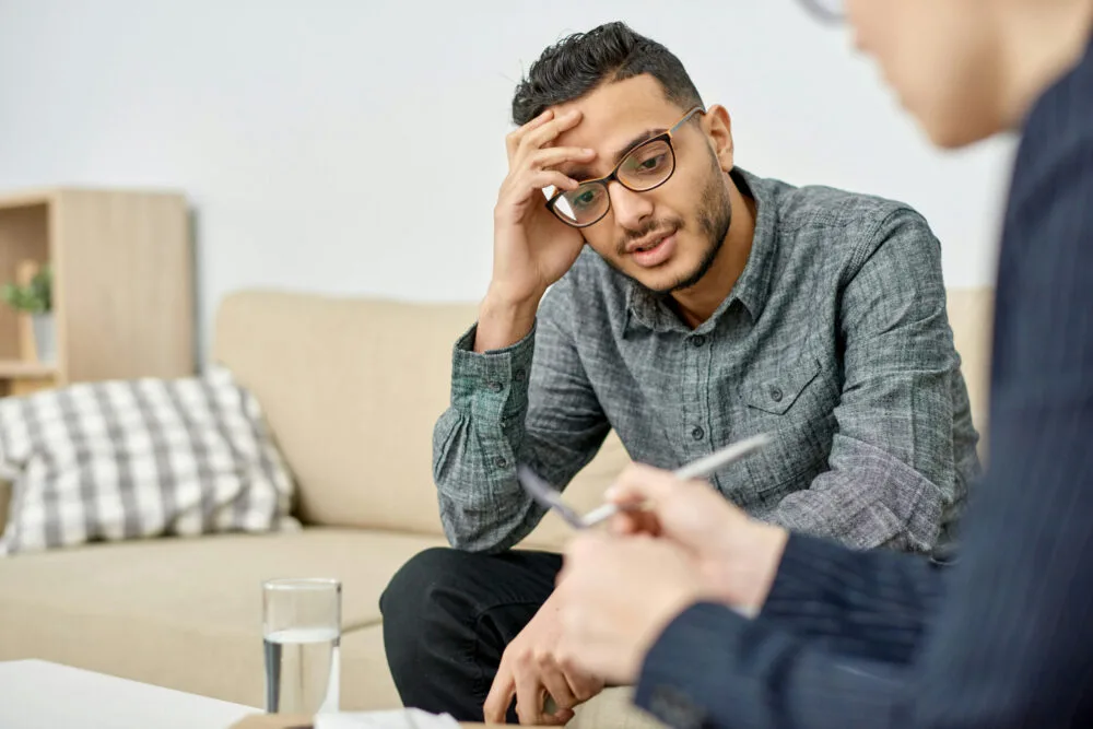 A male client speaking with a recovery coach during a one-on-one counseling session